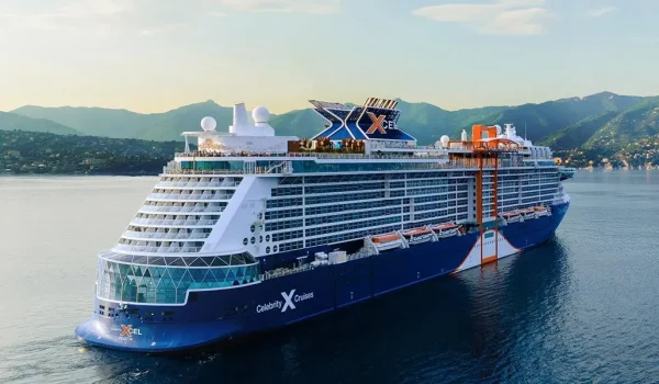 Celebrity X cruise ship floating near a scenic coastal area, showcasing its modern and expansive design