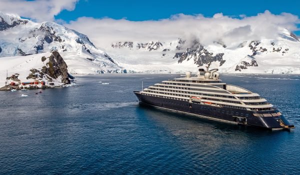 Scenic luxury cruise ship navigating through icy waters, surrounded by snow-capped mountains in Antarctica