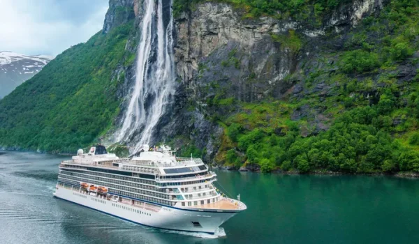 Viking cruise ship sailing along a scenic fjord with a majestic waterfall in the background